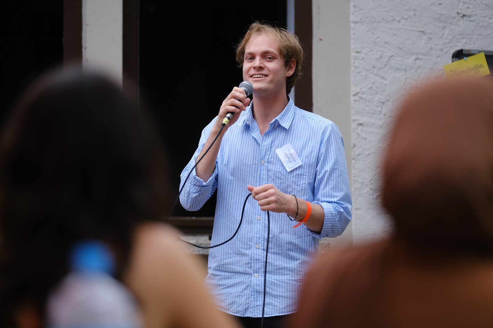 Ein Alumnus spricht lächelnd mit Mikrofon vor Publikum